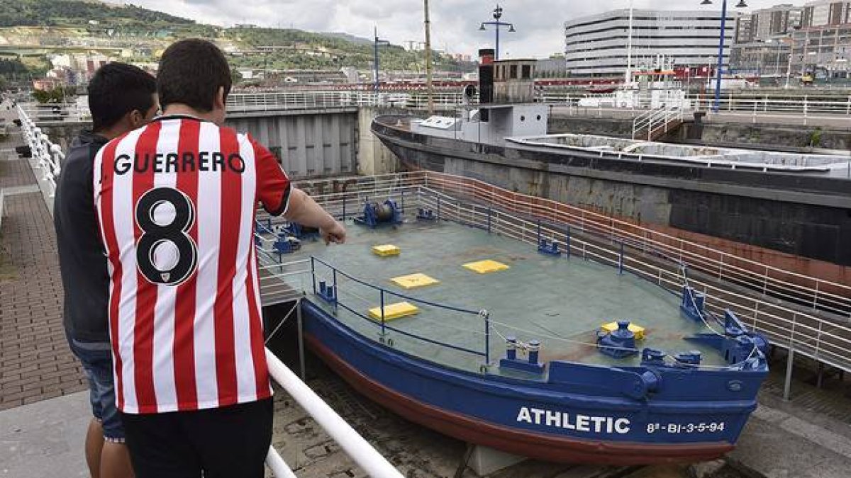 Dos jóvenes observan la gabarra con la que el Athletic Club celebró sus títulos en 1983 y 1984, que no saldrá del Museo Marítimo de Bilbao para festejar la Supercopa de España.