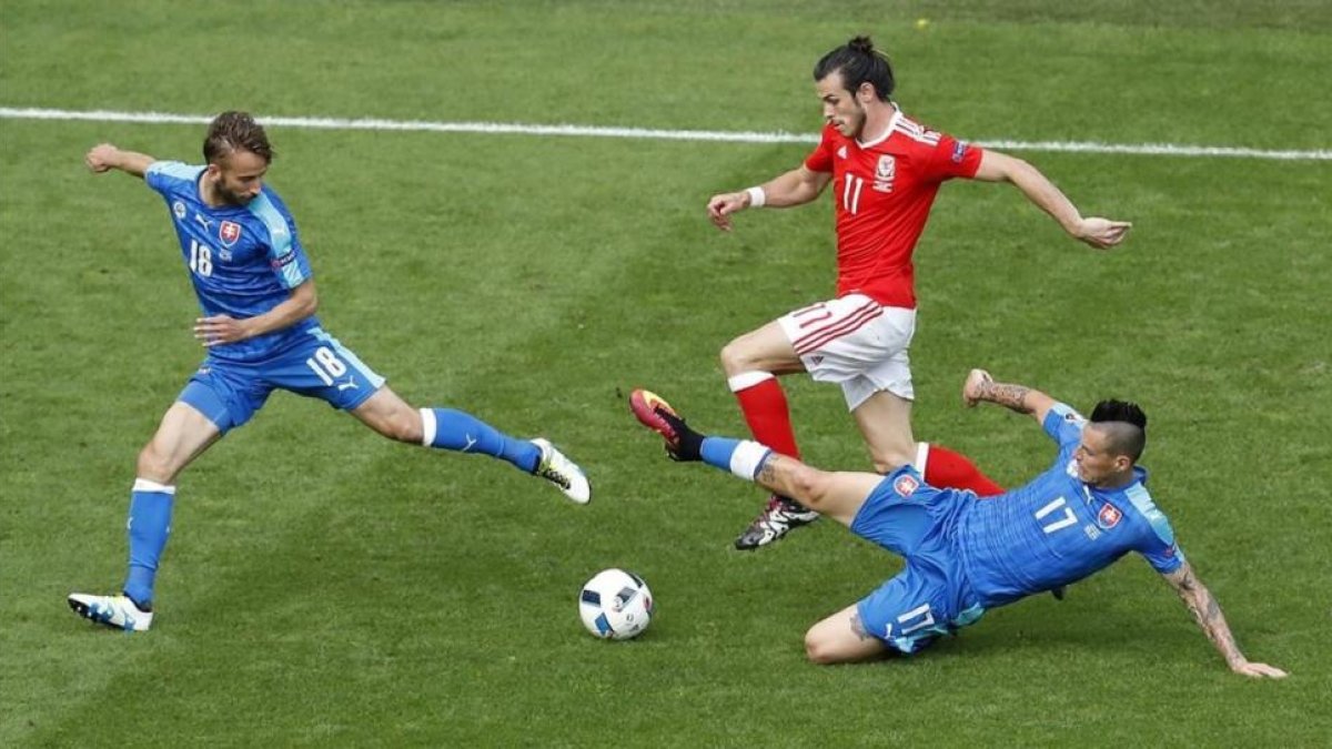 Bale conduce el balón perseguido por dos rivales en el partido inaugural de Gales.