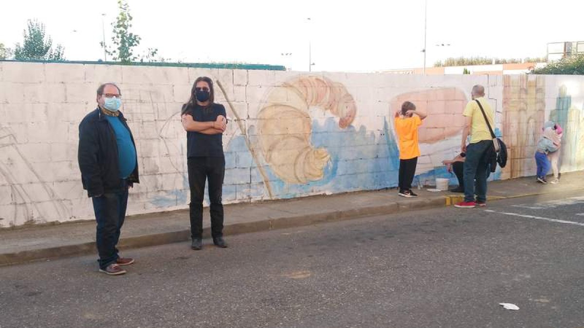 El alcalde bañezano, junto al dibujante frente a un mural. DL