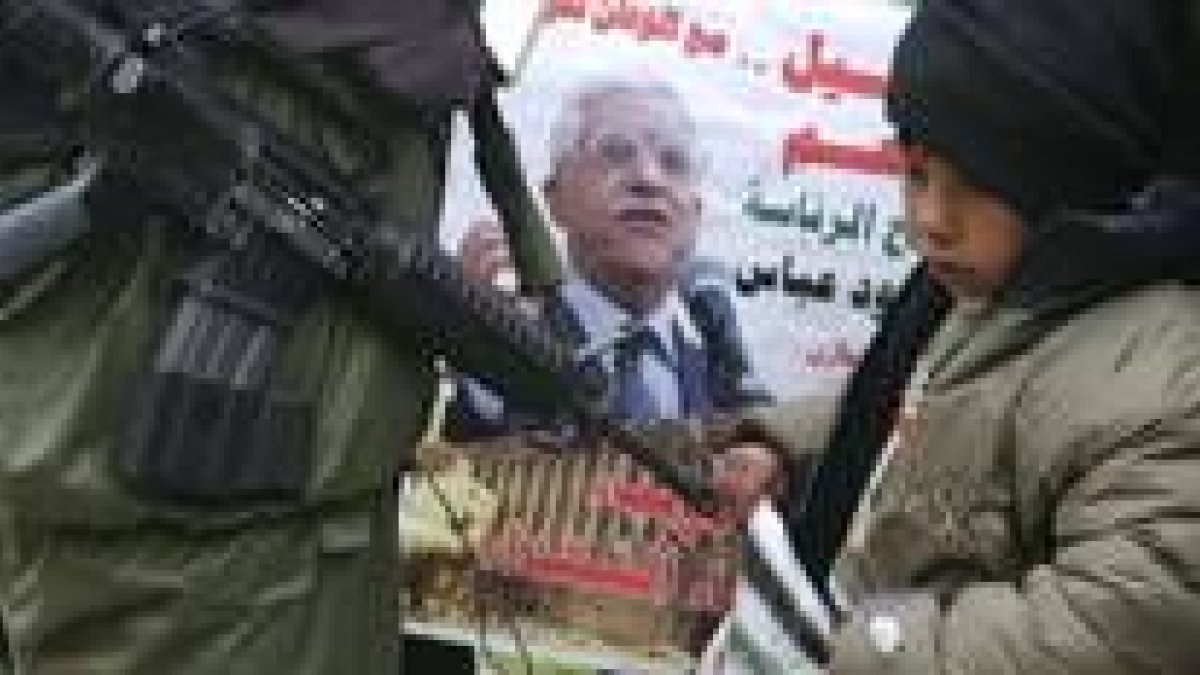 Un niño palestino delante de un cartel de Abú Mazen en Hebrón