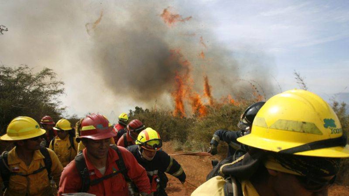Bomberos huyen del fuego después de que más de 60 casas fuesen arrasadas por las llamas en La Cruz y Mariposas.