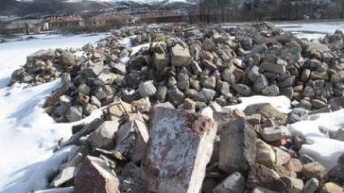 Restos de piedras de la casona depositadas en una finca a las afueras de Puebla de Lillo.