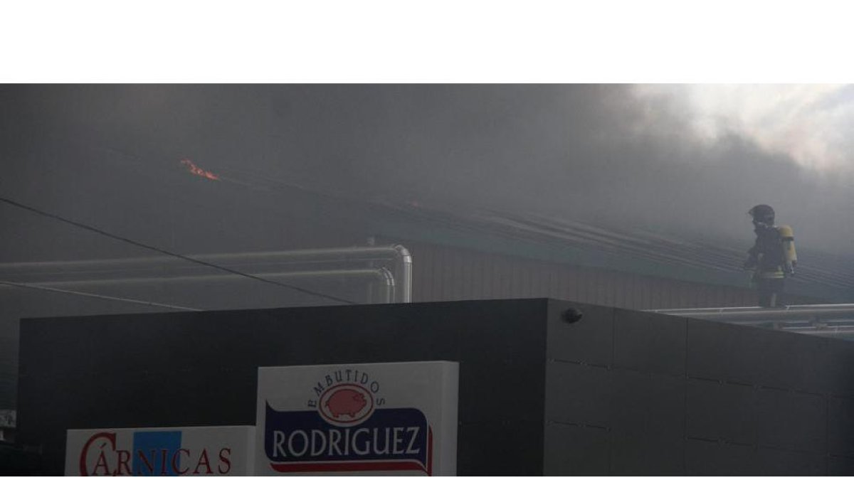 Un bombero en los tejados de la Embutidos Rodríguez en Soto de la Vega