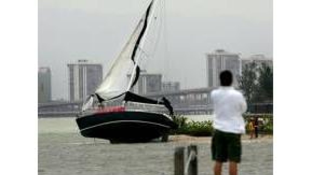 Un hombre observa un bote encallado en Key Biscayne, Miami