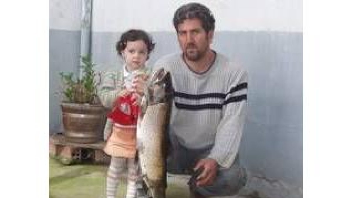Manuel González muestra la trucha pescada acompañado de su sobrina Andrea