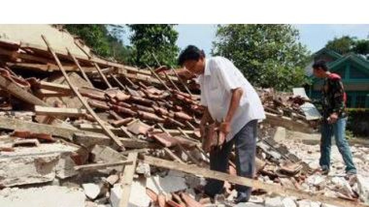 Dos hombres intentan rescatar algunas de sus pertenencias sepultadas bajo los escombros de su casa.
