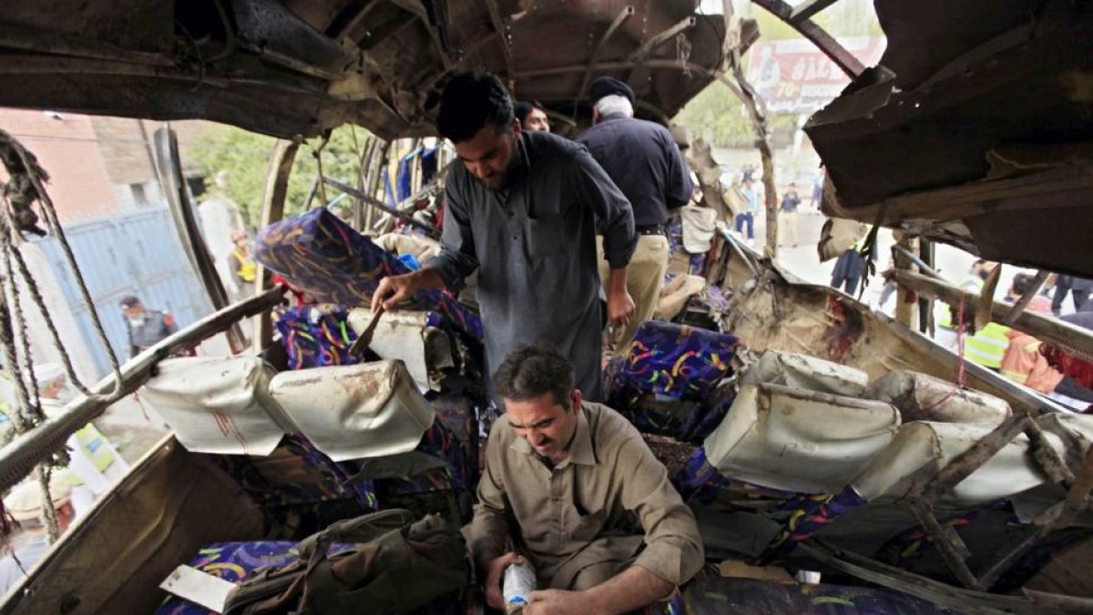 Miembros de las Fuerzas de Seguridad inspeccionan un autobús que ha sufrido un atetado con bomba en Peshawar.