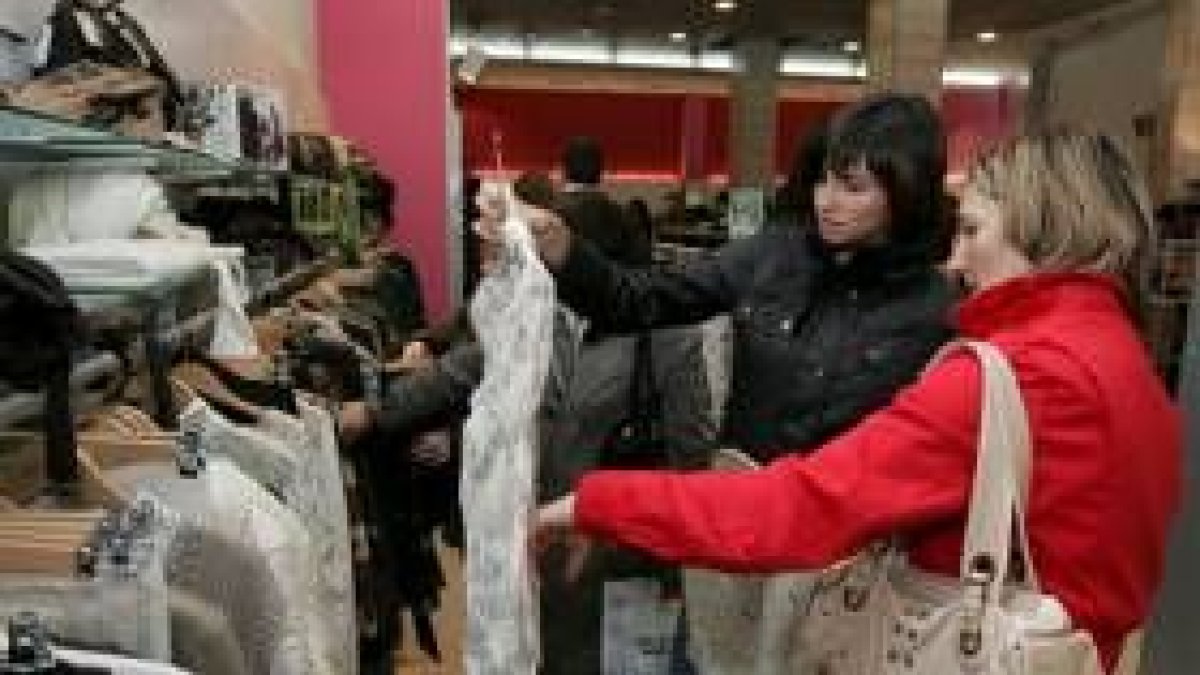 Una madre y su hija comprueban el descuento de una camisa en una céntrica tienda de Ponferrada