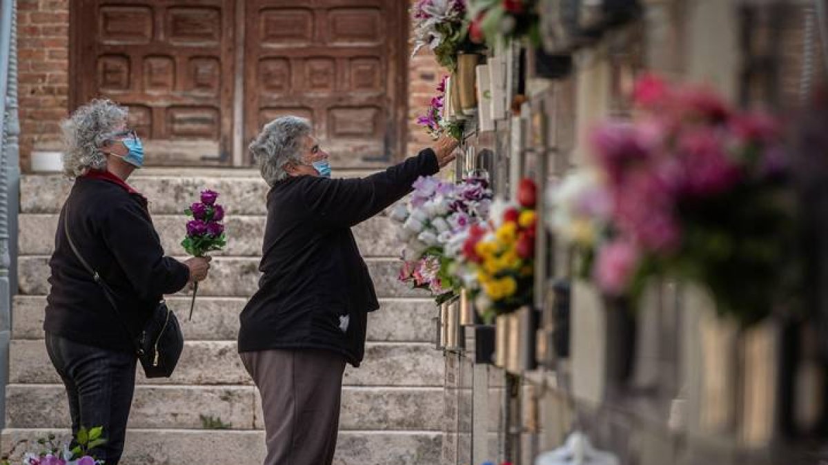Varias mujeres colocan flores en una tumba del cementerio de Alcalá de Henares. FERNANDO VILLAR
