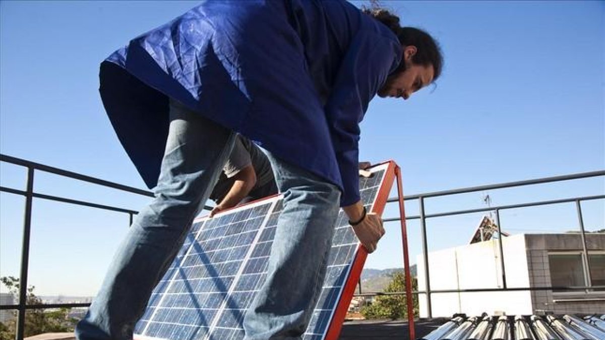 Un hombre instala placas fotovoltaicas en la cubierta de un edificio.