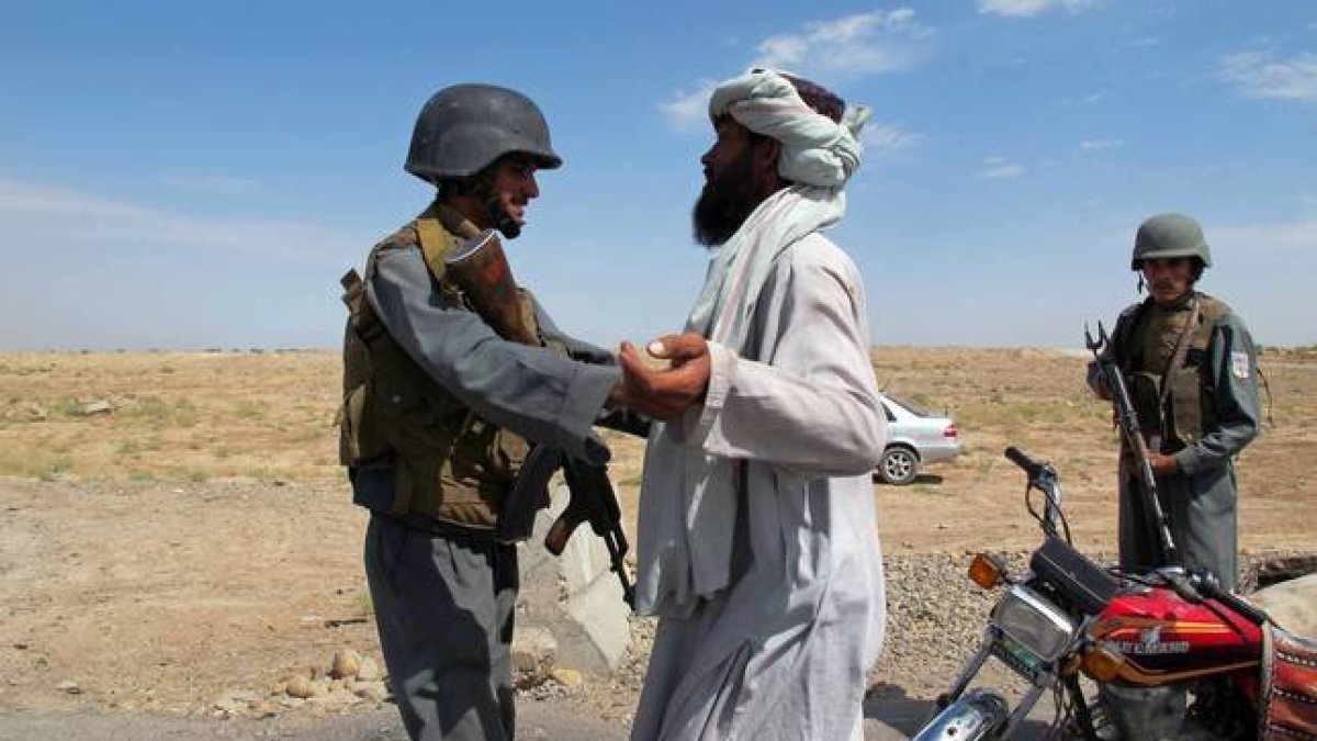 Un policía afgano cachea a un ciudadano en un punto de control en la ciudad de Lashkar Gah tras la fin del proceso de paz.