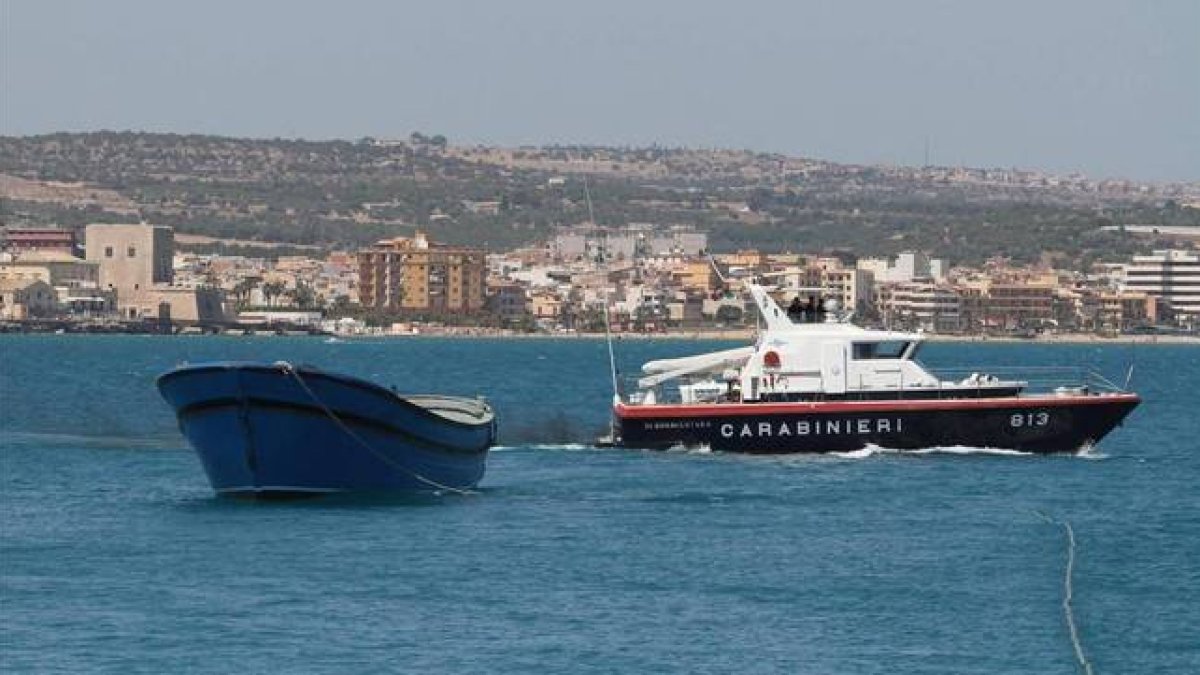 La barcaza con los cuerpos sin vida de 45 inmigrantes muertos por asfixia es trasladada al puerto de Pozzallo, este martes.