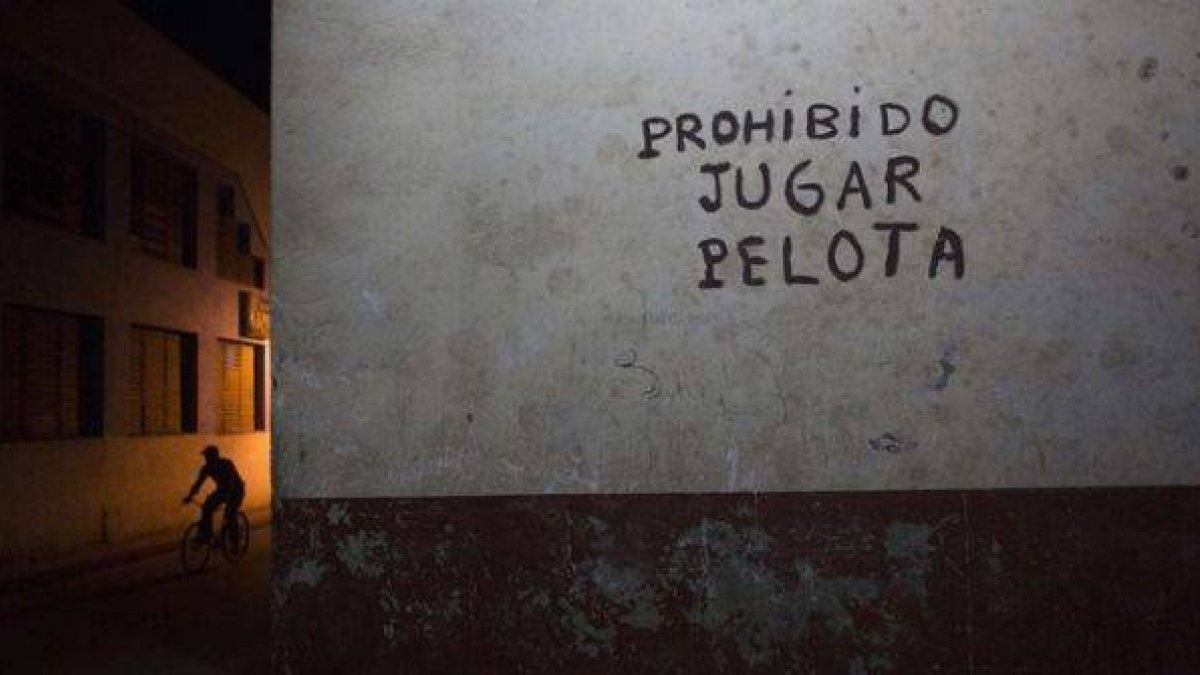 Un ciclista junto a un cartel en el centro de La Habana.