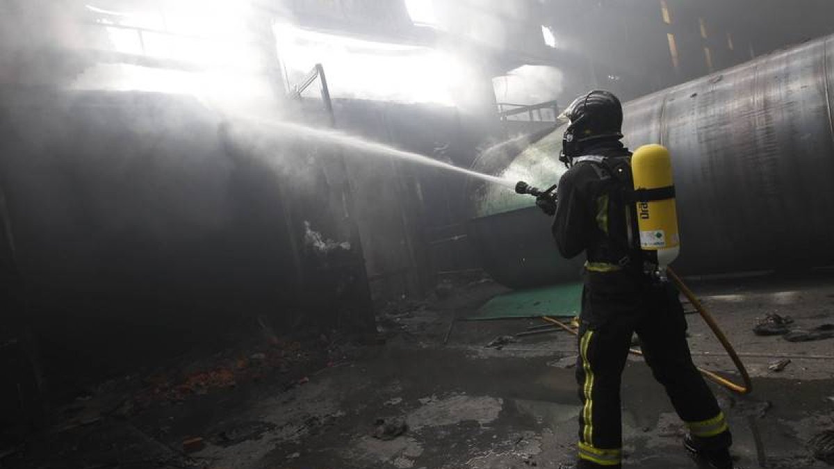 Un bombero apaga un incendio en una nave en Villamañán