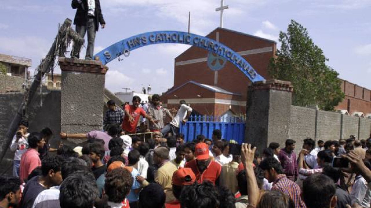 Los cristianos paquistanís y los equipos de rescate se reúnen fuera de una iglesia dañada por un ataque suicida.