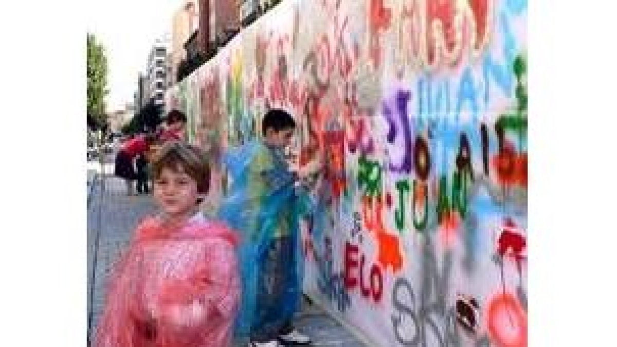 Varios aprendices de grafiteros ensayan su arte en un muro preparado a tal efecto en Ordoño II