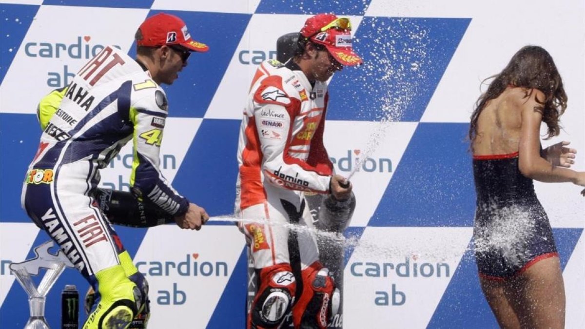 Valentino Rossi y Toni Elias rocían a una azafata con champán en el podio de Brno, en el 2009.