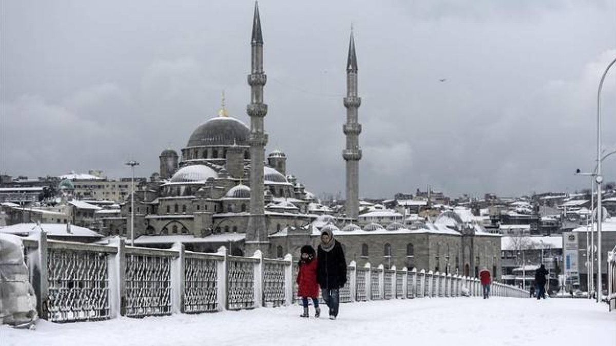 Varios transeúntes caminan por un nevado puente de Galata, en Estambul, este miércoles.