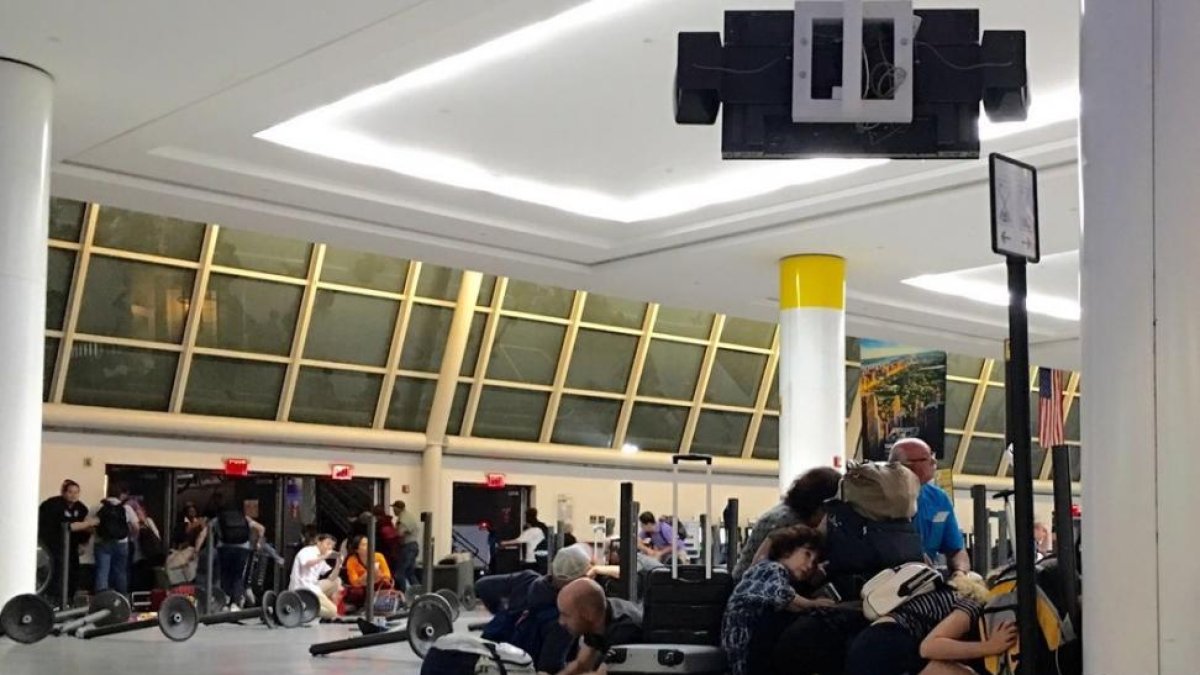 Pasajeros del aeropuerto JFK de Nueva York se protegen mientras la policía busca a un presunto tirador, la pasada madrugada.