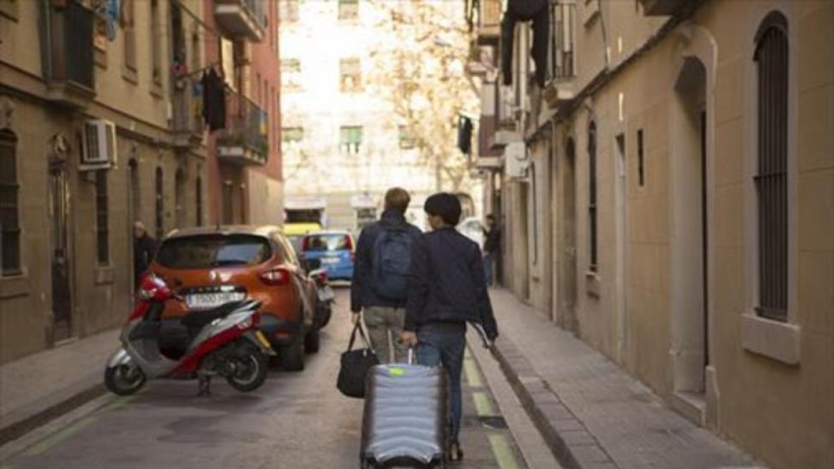 Dos turistas con su equipaje en una calle de la Barceloneta.