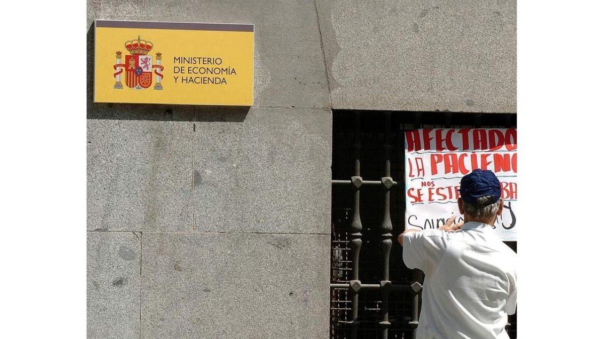 Un hombre coloca una pancarta en la fachada del Ministerio de Hacienda VÍCTOR LERENA
