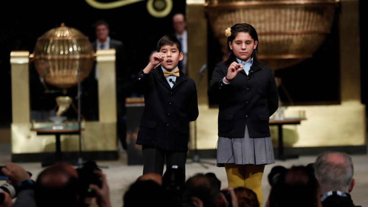 Nerea Pareja Martínez y Alonso Dávalos Durán, primera pareja de niños en el sorteo Extraordinario de la lotería de Navidad, muestran el segundo premio del sorteo.