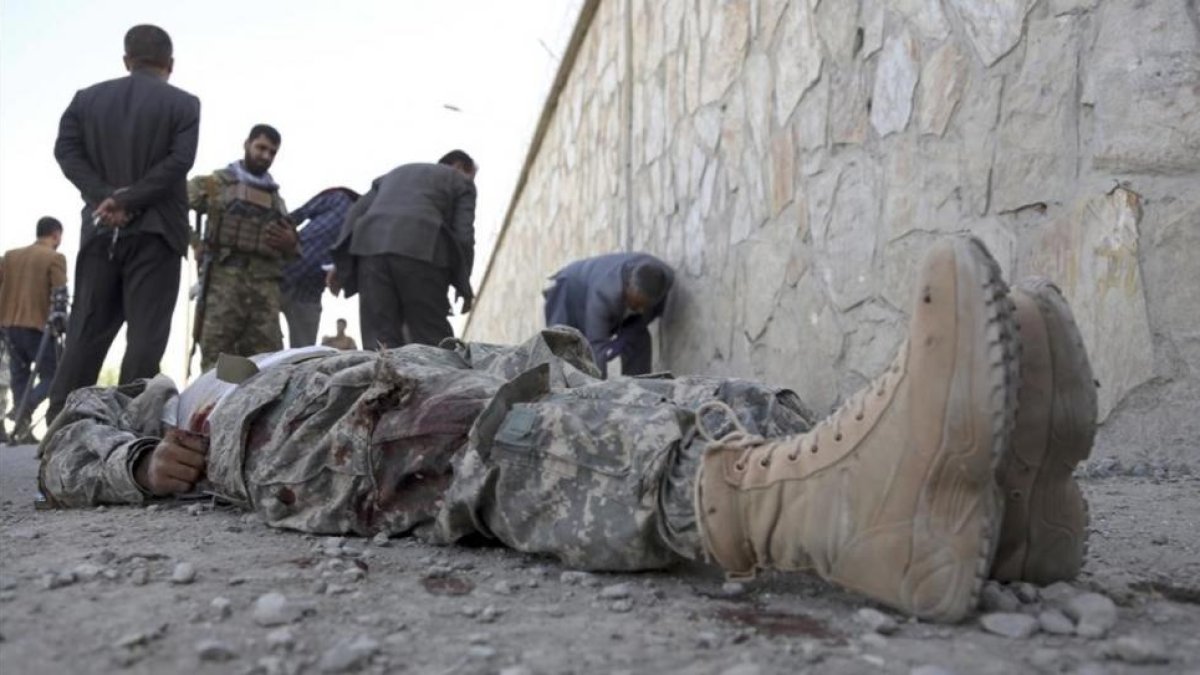 Militares inspeccionan el cadáver de un miliciano en la sede del Ministerio del Interior afgano, en Kabul.