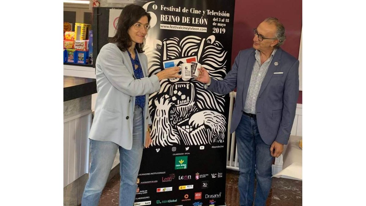 María Oliden y Tomás Martínez Antolín brindan ayer ante el cartel del Festival de Cine y TV Reino de León. DL