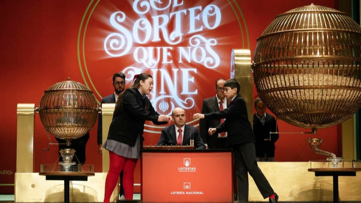 Daniela Laborde Valverde (i) canta los números junto a su compañero Francisco Moreno Durán (d), que canta los premios, durante el sorteo de El Gordo de Navidad en el Teatro Real en Madrid. JAVIER LIZÓN