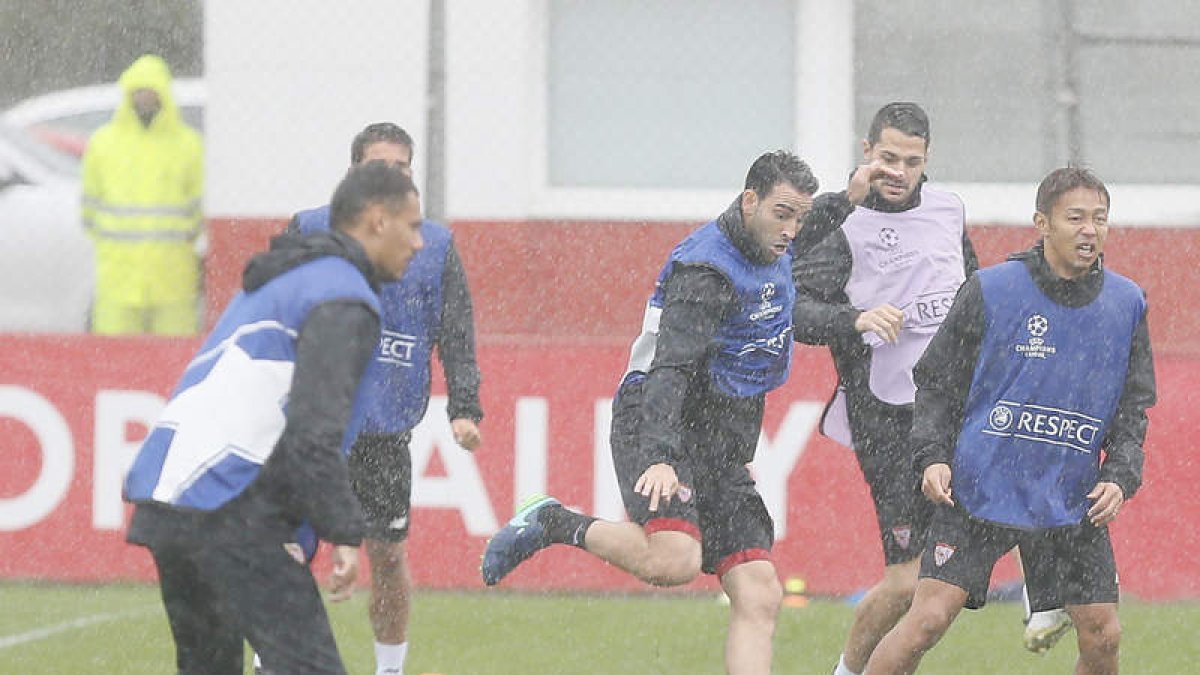 Los jugadores del Sevilla durante el entrenamiento realizado ayer, en el que no dejó de llover. J. M. VIDAL