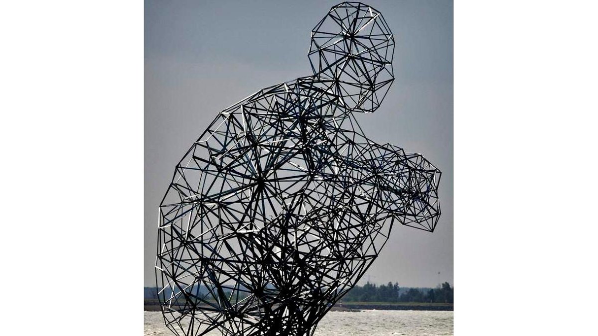 Imagen de la escultura gigante de un hombre agachado situada en una presa de Lelystad, Holanda