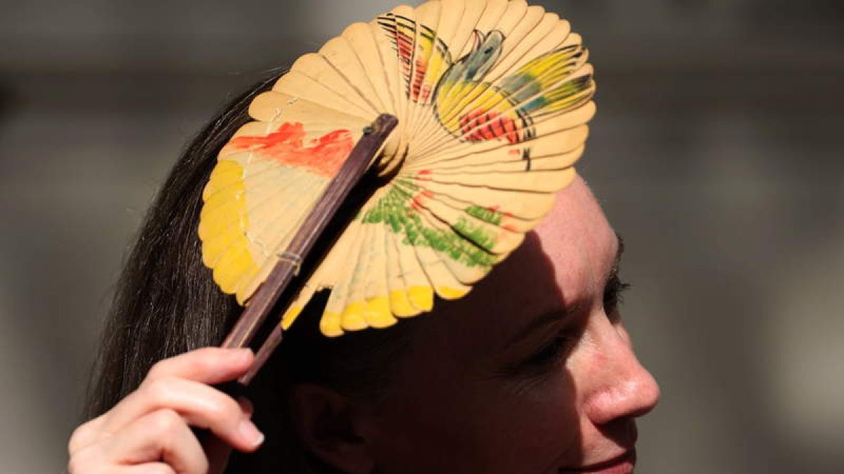Una mujer utiliza un abanico para protegerse del sol. NEIL HALL
