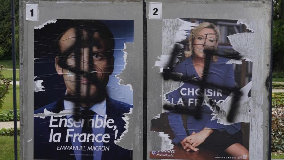 Pintadas en carteles electorales de Macron y Le Pen.