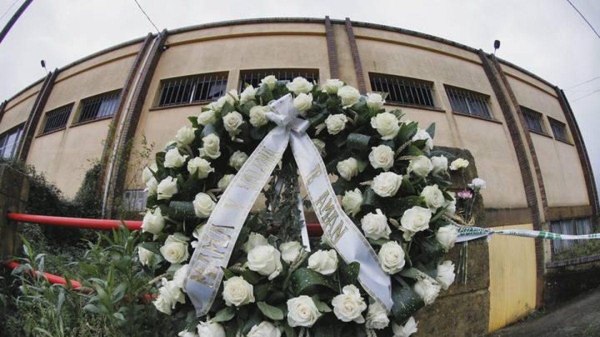 Una corona de flores con la inscripción, "Mamá y Valeria te aman", se ha colocado esta mañana en el altar improvisado ante la nave donde fue hallado el cuerpo sin vida de Diana Quer, en el lugar de Asados, en Rianxo (A Coruña).