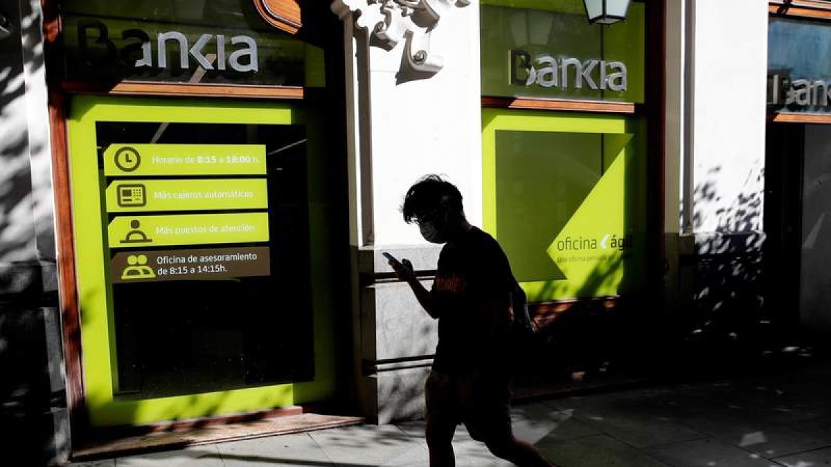 Una persona camina por el centro de Madrid delante de una sucursal de Bankia. JUAN CARLOS HIDALGO