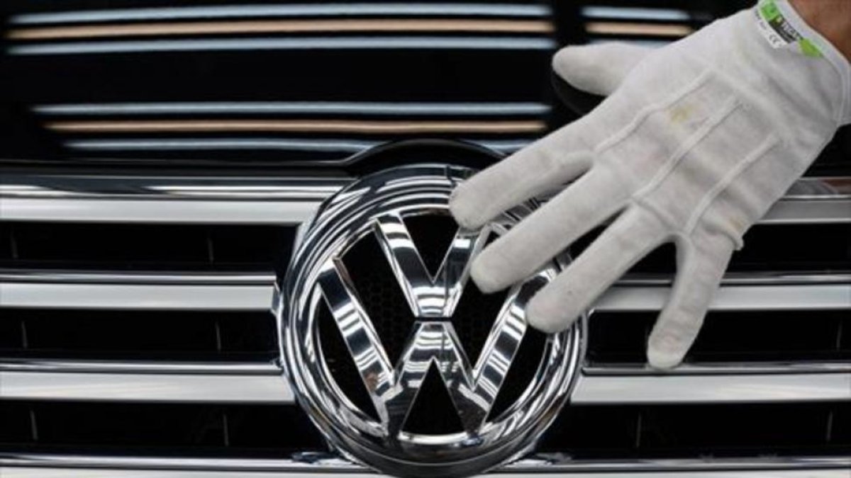 Un empleado coloca el logotipo de Volkswagen a un vehículo.