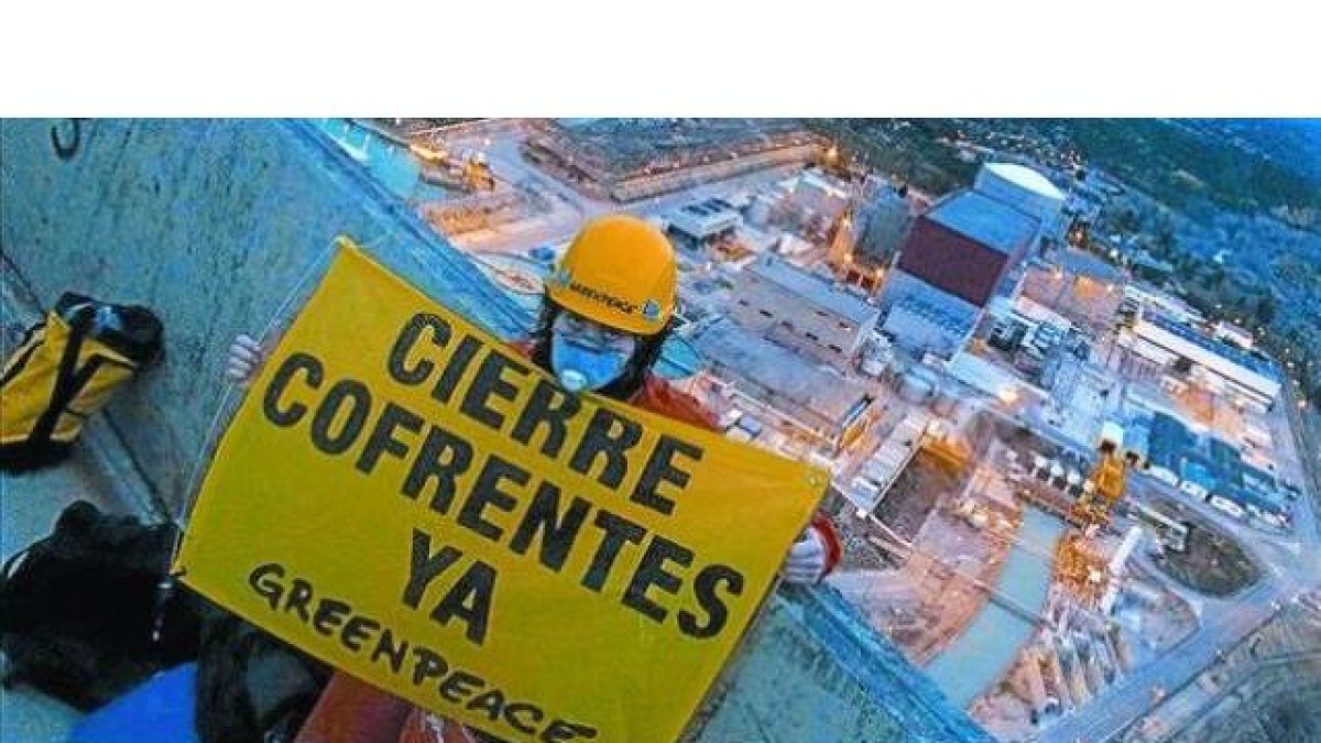 Un activista de Greenpeace, con un cartel en una de las torres de refrigeración de Cofrentes.