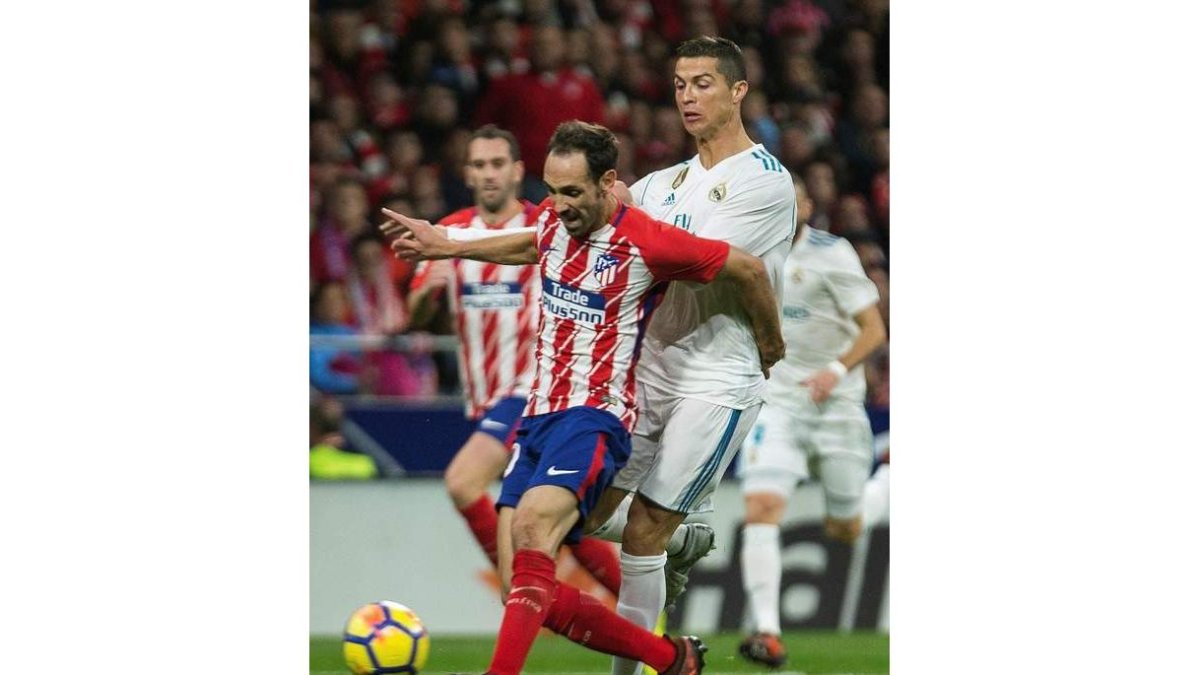 El delantero portugués del Madrid Cristiano Ronaldo pelea un balón con el defensa del Atlético Juanfran Torres. RODRIGO JIMÉNEZ