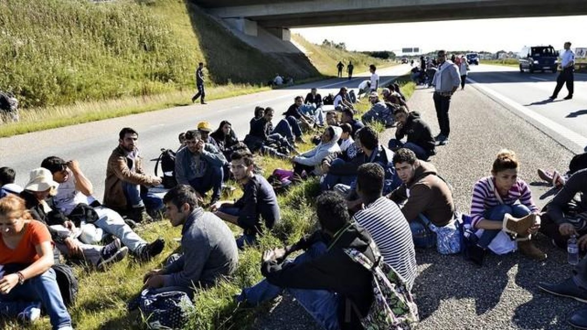 Un grupo de refugiados descansan en medio de una autopista en el sur de Dinamarca.