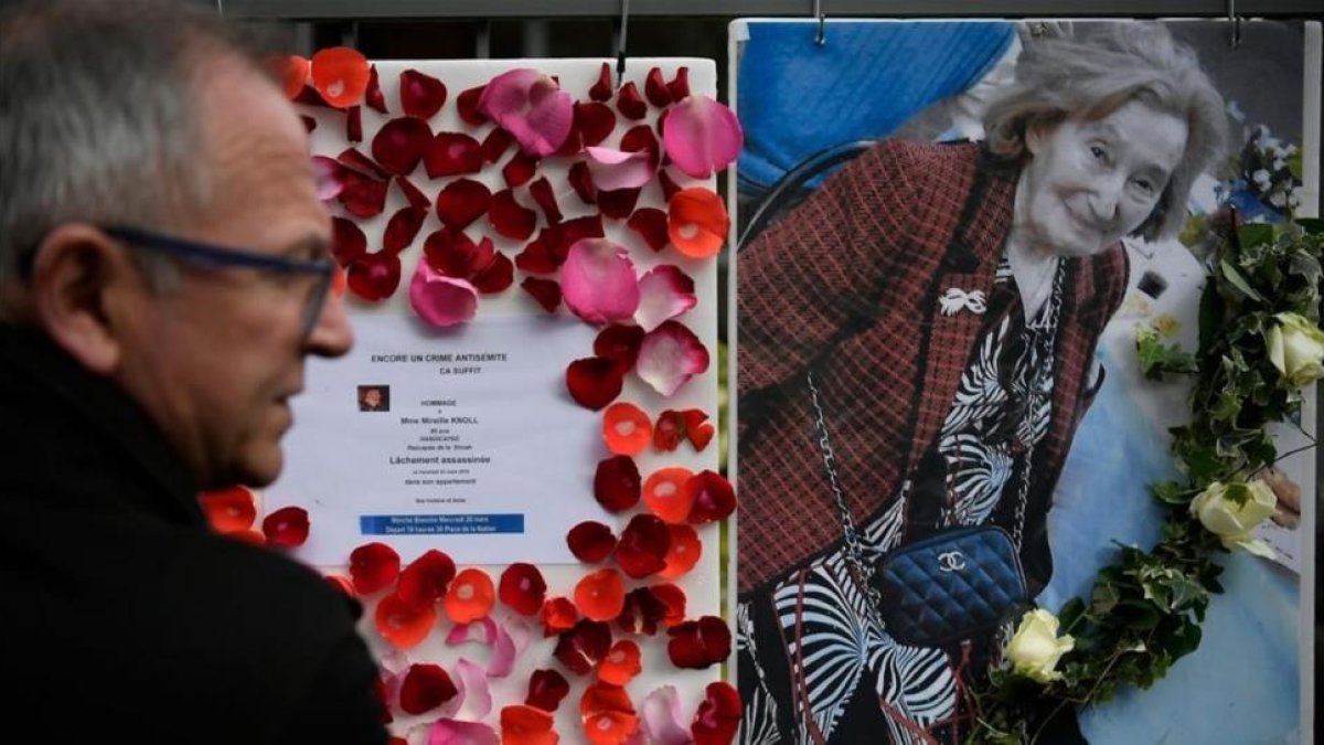 Una hombre mira una foto de Knoll y la convocatoria a una marcha de protesta por su asesinato, en París.