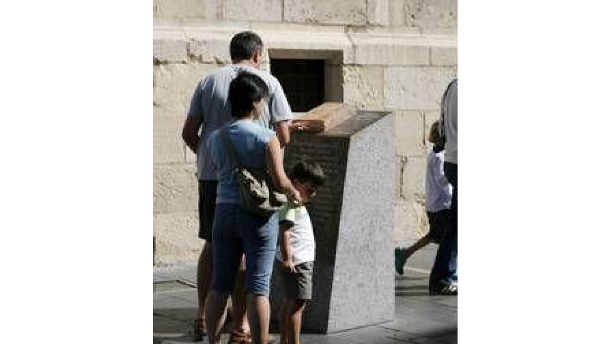 Una familia observa uno de los monolitos que señalizan la ruta