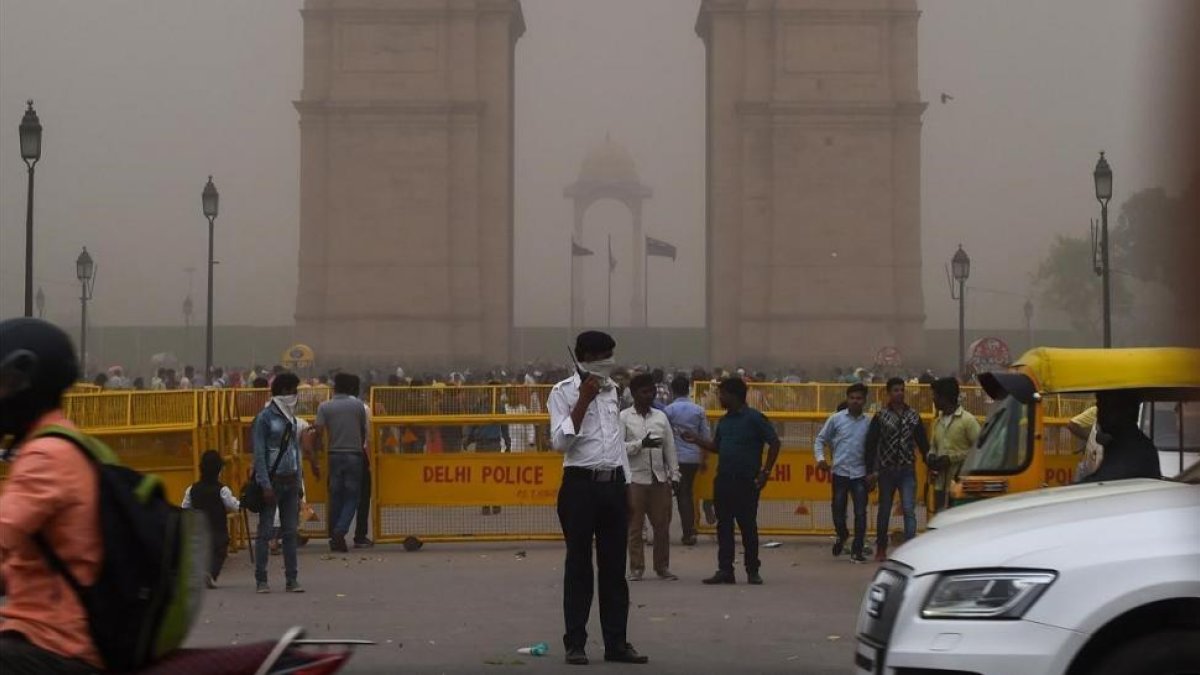 Un agente de policía de Nueva Delhi dirige el tráfico mientras se cubre la cara en medio de una tormenta de arena.