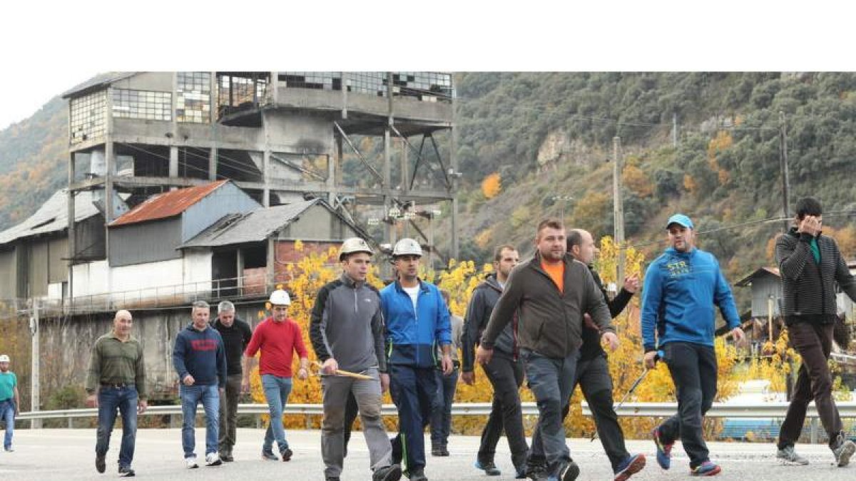 Un grupo de los trabajadores que participan en la marcha, a su paso por Santa Cruz del Sil, junto al viejo lavadero de carbón que es el símbolo de una época dorada. L. DE LA MATA