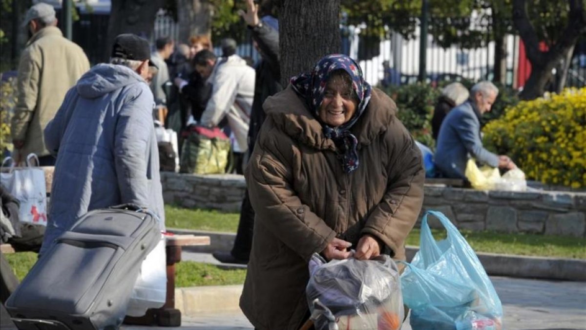 Una anciana sintecho recoge sus pertenencias en Atenas.