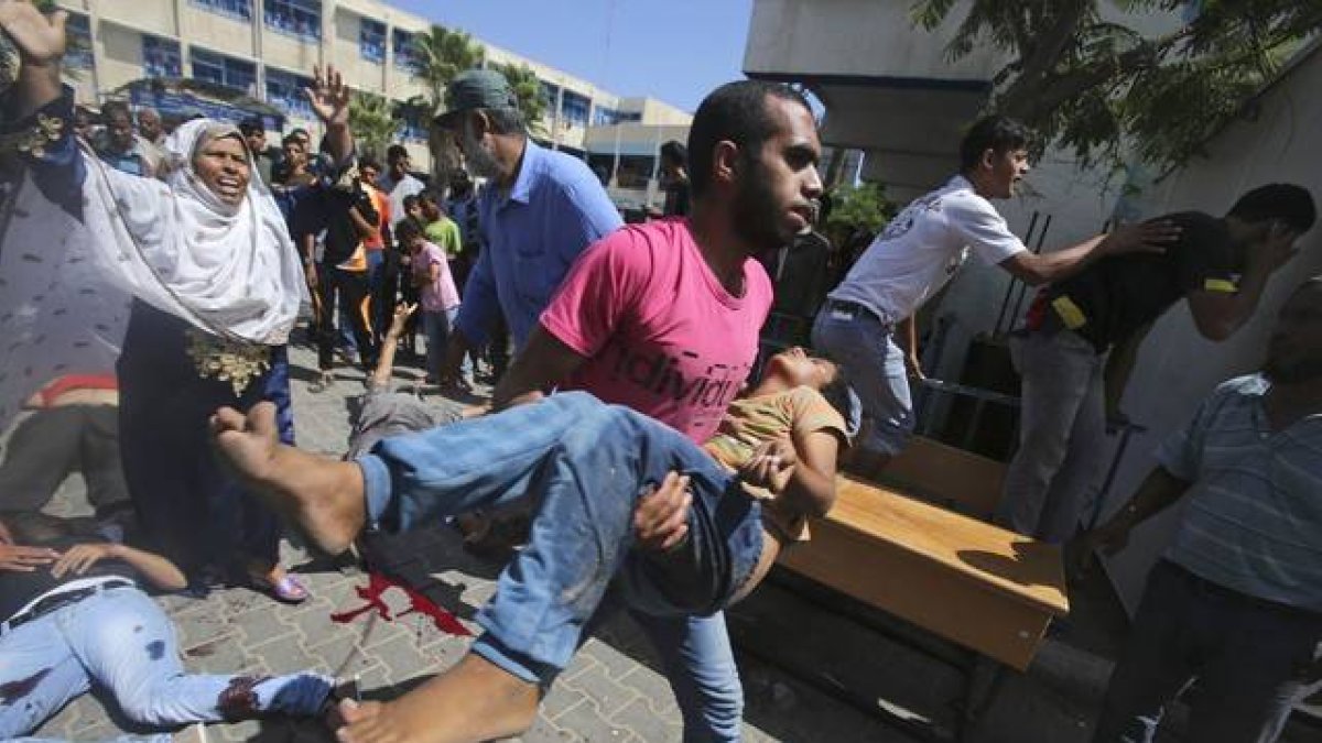 Un palestino traslada a un niño herido en el ataque a una escuela de la ONU en Rafah.