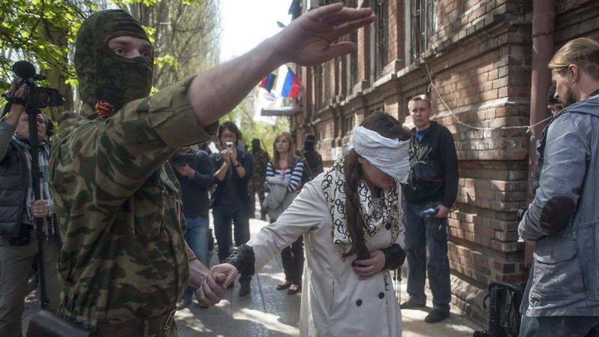 Un hombre conduce a la activista y periodista ucraniana Imra Krat, retenida por prorrusos.