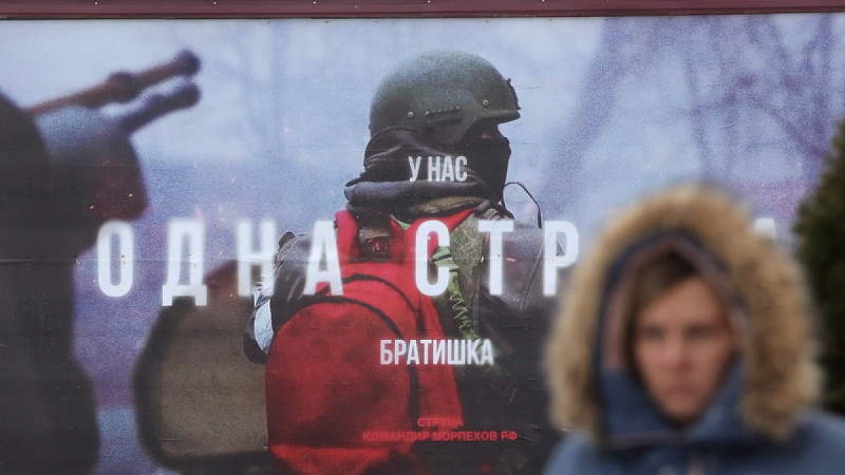 Una mujer pasa ante un cartel que representa a un soldado ruso ayer, en Moscú. MAXIM SHIPENKOV