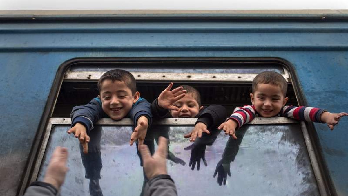 Niños saludan desde un autobús con destino a Serbia. G. LICOVSKI