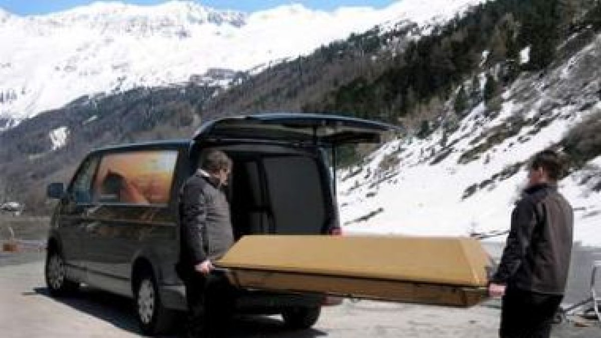Dos operarios trasladan el ataúd de uno de los fallecidos en los Alpes
