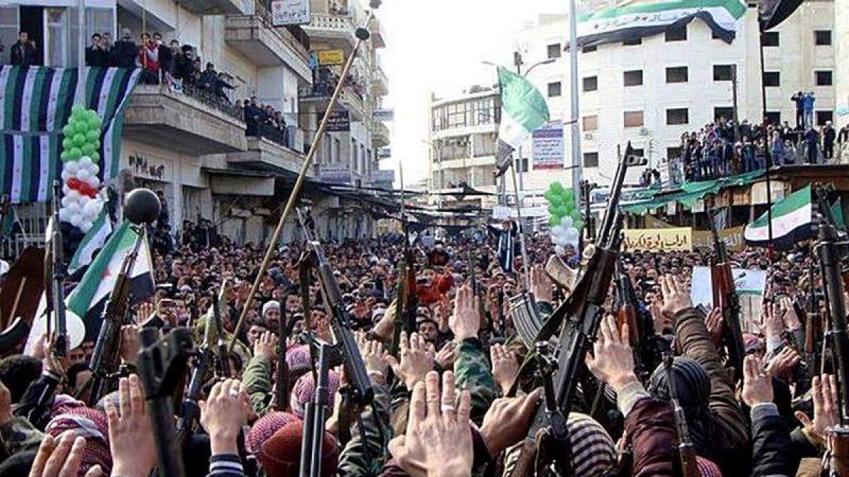 Ciudadanos sirios con sus armas en alto y banderas revolucionarias ondeando durante una protesta en Damasco.